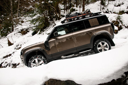side view of modern off-road car ride on snowy road at mountains. Mountain tourism transport.