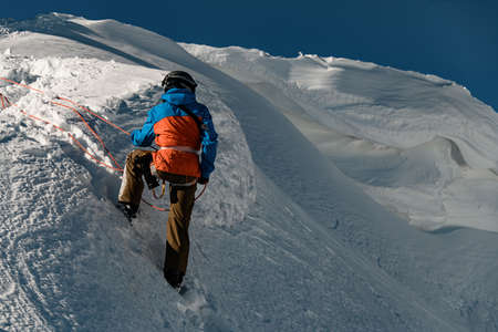 rear view of man in ski suit holding rope on mountain slopeの写真素材