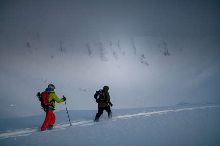 tourists going on ski tour in winter mountains on background of snowy mountain slopeの写真素材