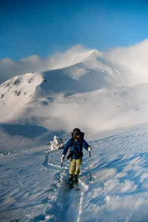 Male skier walking on deep white powdery snow path of snow-capped mountain Shpytsy in Ukraineの写真素材