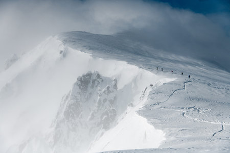 beautiful view of the high snow-capped mountain range and skiers walking along it