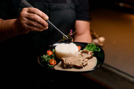 Male hand hold plate of dish and decorate it with a rosemary branch