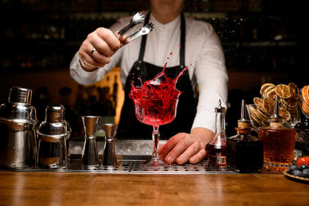 great view on bar counter with a variety of bar equipment and goblet with splashing drinkの写真素材