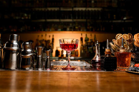 wonderful view of goblet with drink on the bar counter and bar equipment around it. Blurred bar background.の写真素材