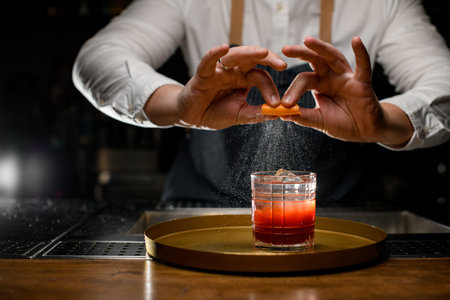 selective focus on glass with alcoholic beverage and male hands carefully sprinkle by citrus zest...