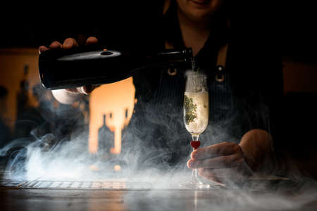 amazing view of champagne glass and hand of bartender pouring a drink from bottleの写真素材