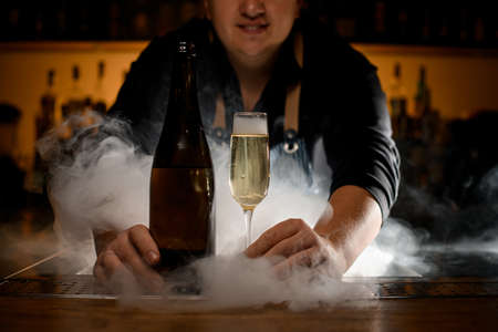 excellent view of champagne glass with drink and bottle at smoked barの写真素材