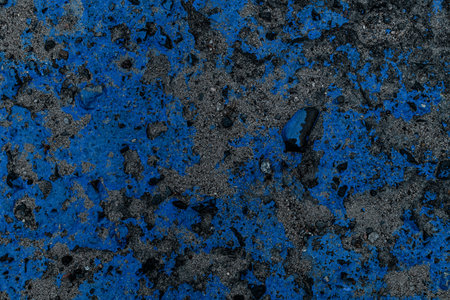 Close-up view of asphalt surface with stones covered with blue paint spots.の写真素材