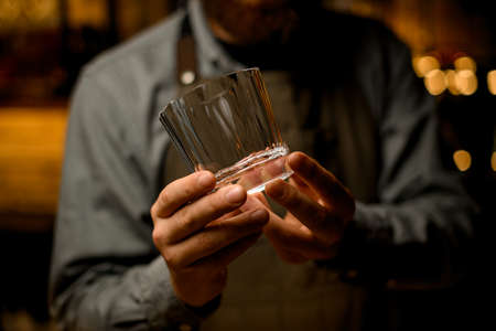 Close-up of beautiful empty glass for drink in male bartender hands.の写真素材