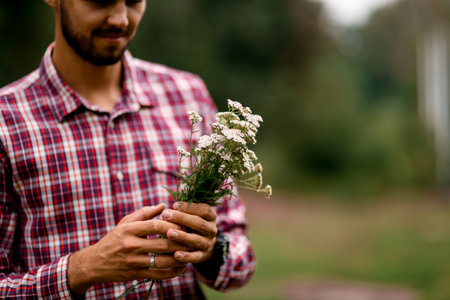 selective focus on beautiful white wildflowers in the hands of a manの写真素材