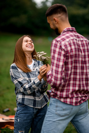 gorgeous view of happy young woman and man giving her wildflowersの写真素材
