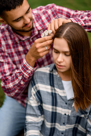close-up of beautiful young woman whose man decorates her hair with flowersの写真素材