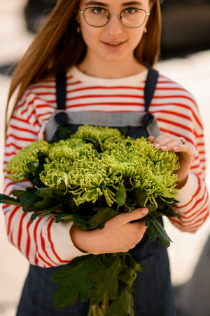 woman holds bouquet of fresh green chrysanthemum flowers in her handsの写真素材