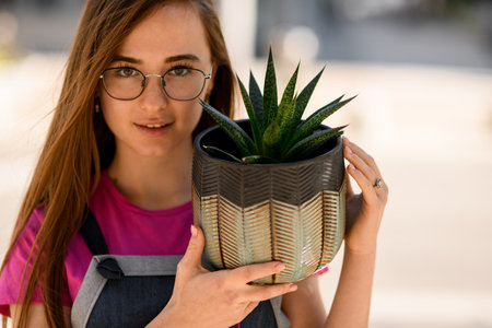 Close-up portrait of woman with decorative green plant haworthia in pot.の写真素材