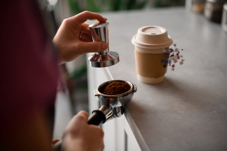 Female hand masterfully tamping ground coffee into portafilterの写真素材