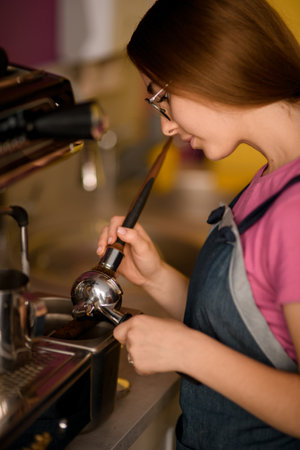 Close-up view on woman barista tamping coffee in portafilter with tamper.の写真素材