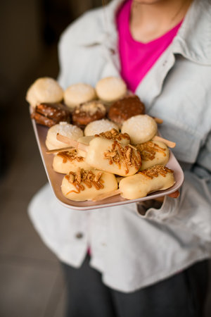 selective focus on macarons in the form of ice cream with stick covered with chocolate icing on tray in female hands.の写真素材