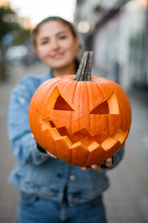 selective focus on beautiful bright orange pumpkin with carved smiling face in female handsの写真素材
