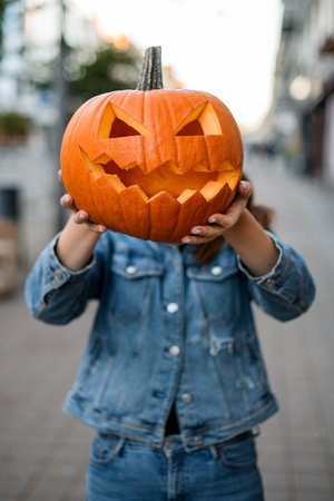 great view on beautiful bright orange pumpkin with carved smiling face in female handsの写真素材