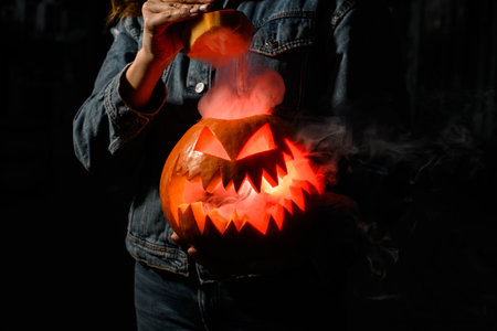 magnificent halloween pumpkin with burning and smoking mouth and eyes in female hands. Jack-o-lanternの写真素材