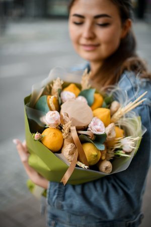 focus on beautiful bouquet with flowers and fruits of lemon and ginger which woman holdsの写真素材
