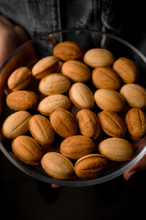 Close-up top view on walnut shaped cookies in plate in female handsの写真素材