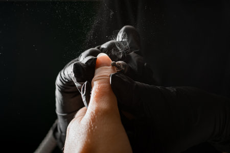 Close-up of hands of manicurist in gloves files nails on woman hand with professional electric nail drillの写真素材
