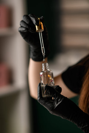 selective focus on vial with essence and pipette with digging liquid in female hands