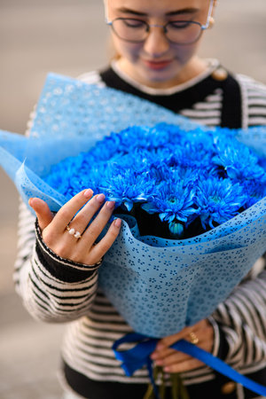 focus on flower bouquet of blue chrysanthemums in wrapping paper in female handsの写真素材