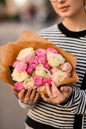 Close-up view of bouquet of fresh roses in wrapping paper in female handsの写真素材