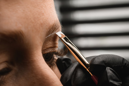 close-up on brush with white paste which makeup artist makes markings for eyebrow correctionの写真素材