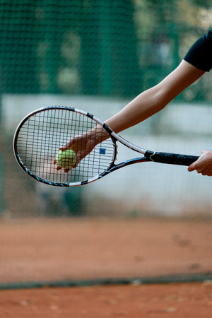 Close-up view of hand female tennis player holding ball and racket preparing to serve