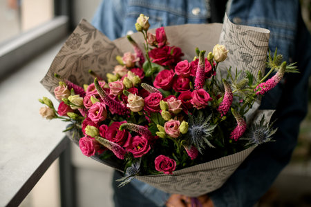 close-up on flowers of roses and thistle and lupine in bouquet in wrapping paper