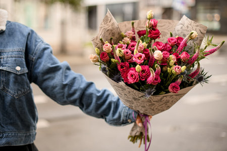 close-up on bouquet of roses and thistle and lupine in in outstretched handの写真素材