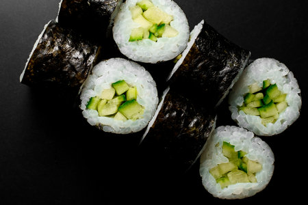 Close-up top view on kappa maki sushi rolls with cucumbers and rice wrapped in nori on dark backgroundの写真素材