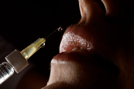 great close-up view of syringe needle with drop of the drug near the female lips. Lip augmentation.の写真素材