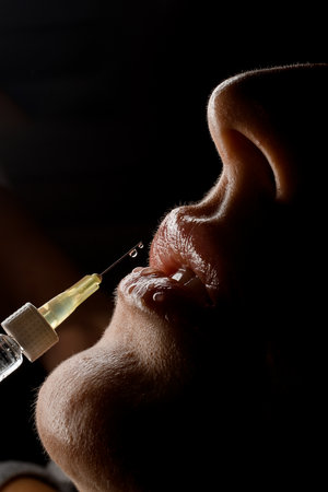 great close-up side view of syringe needle with drop of the drug near the female lips. Lip augmentation.の写真素材