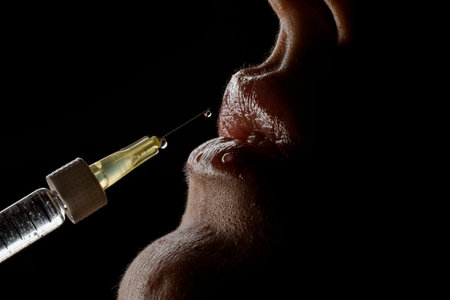 close-up side view of syringe needle with drop of the drug near the female lips. Lip augmentation.の写真素材
