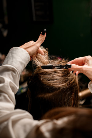 close-up of hands of woman hairdresser neatly fasten hair of female client with hairpin.の写真素材