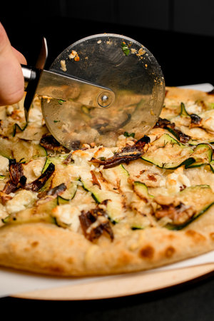 selective focus on pizza cutter which cut tasty vegetarian pizzaの写真素材