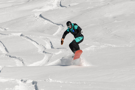 Freerider on snowboard skillfully jump at white fresh snow of mountain slopeの写真素材