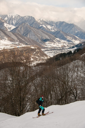 Picturesque view of male skier walking against beautiful winter mountain landscape