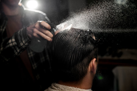 back view of head hair of male client which barber wets by spray and combsの写真素材