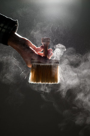 wonderful view on brush in male hand and talcum powder around in the airの写真素材