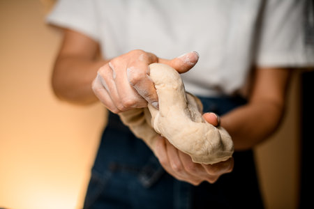 Selective focus on female hands vigorously kneading raw bread doughの写真素材