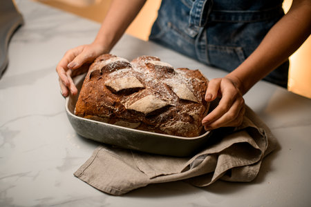 view on tasty freshly baked bread in bakery form which female hands holds.