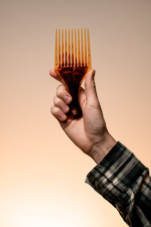 male hand holding barber plastic hair styling afro pick combの写真素材