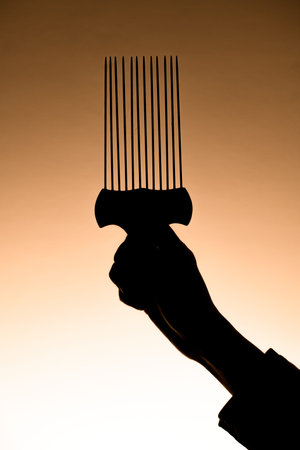 dark silhouette of hand gently holding barber metal hair styling afro pick comb