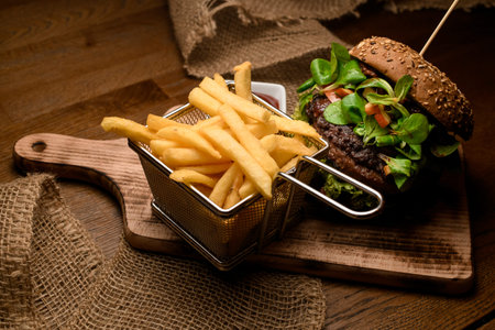 appetizing view on french fries and burger on the wooden board