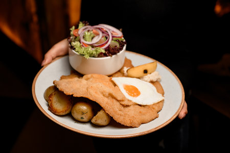 great view on plate with chop with roasted egg and potato and salad in female handsの写真素材
